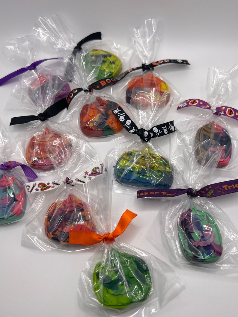 K&ouml;nnte beinhalten: Sortiment an bunten Halloween-Kreiden in Form von K&uuml;rbissen, einzeln verpackt in durchsichtigen Plastikt&uuml;ten mit festlichen B&auml;ndern.