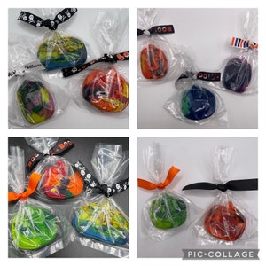 K&ouml;nnte beinhalten: Vier durchsichtige Plastikt&uuml;ten gef&uuml;llt mit bunten, handgefertigten, k&uuml;rbisf&ouml;rmigen Buntstiften. Jede T&uuml;te ist mit einem Band gebunden und mit Halloween-Dekorationen verziert.