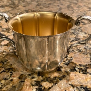 May include: Silver sugar bowl with two handles and a gold interior.