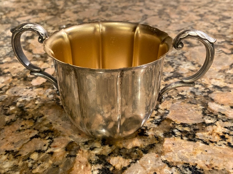 May include: Silver sugar bowl with two handles and a gold interior.