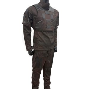 Może przedstawiać: Taktyczny uniform w kolorze ciemnobrązowym i czarnym z kamizelką w kamuflażu. Uniform składa się z koszuli z długim rękawem i spodni.