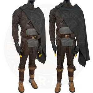 Op de afbeelding: Een bruin en zwart kostuum met een donkergrijze cape. Het kostuum heeft een riem met gesp, een borststuk en beenbedekking. Het kostuum wordt gedragen door een mannequin.