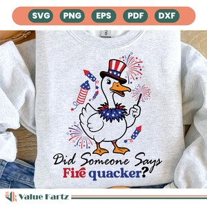 May include: A light gray sweatshirt featuring a cartoon goose wearing a patriotic hat and holding a sparkler. The goose is surrounded by fireworks and rockets. Text on the shirt reads, "Did Someone Says Fire quacker?"