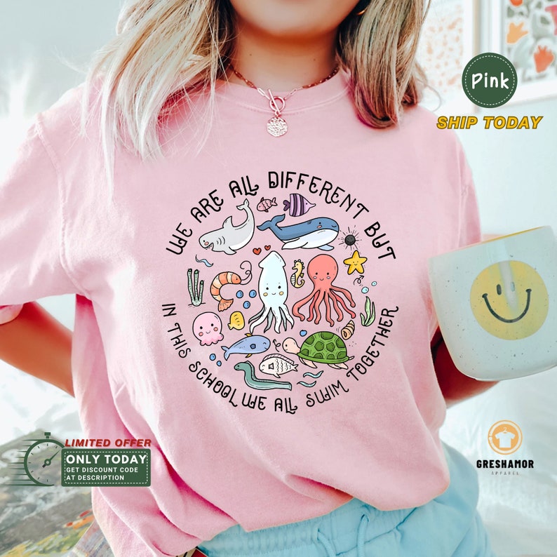 May include: Pink t-shirt with a graphic of sea creatures and the text "We are all different but in this school we all swim together".