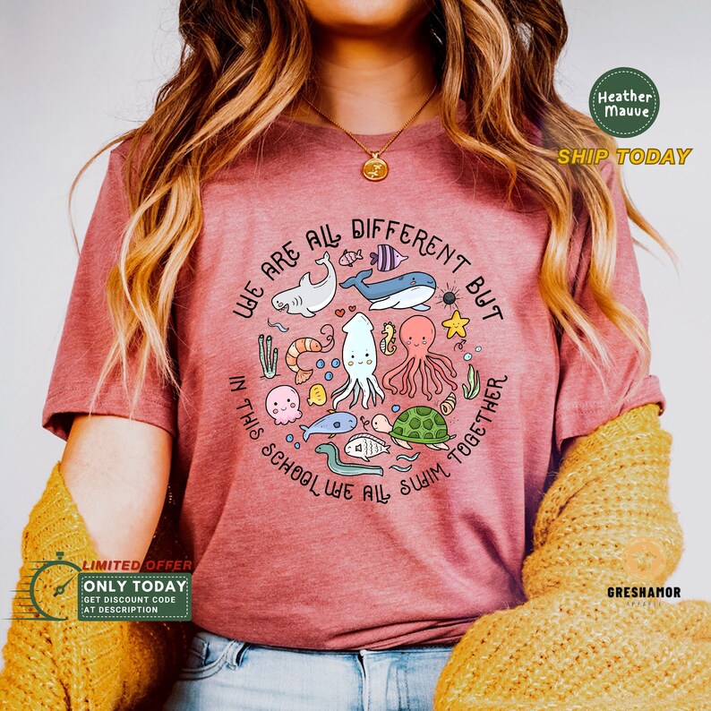 May include: A heather mauve t-shirt with a circle graphic featuring the text "We are all different but in this school we all swim together". The graphic includes a variety of sea creatures, including a shark, whale, octopus, turtle, and fish.