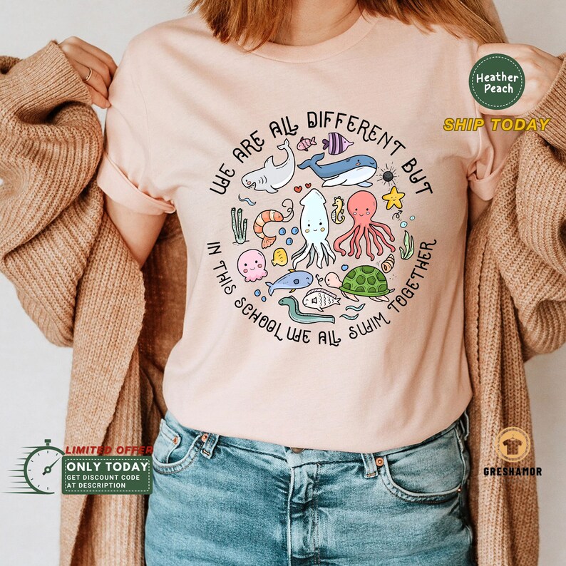 May include: A pink t-shirt with a circle design featuring various sea creatures and the text "We are all different but in this school we all swim together."