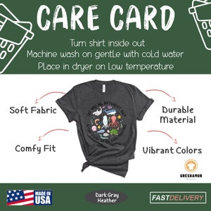 May include: Dark gray heather t-shirt with a graphic of colorful sea creatures and the text "We are all different but in this school we all swim together". The shirt is made in the USA and has a care card with instructions for washing and drying.