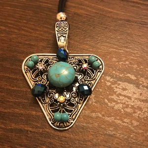 May include: A silver triangle pendant necklace with a turquoise stone and blue and clear rhinestones. The pendant is attached to a black cord.