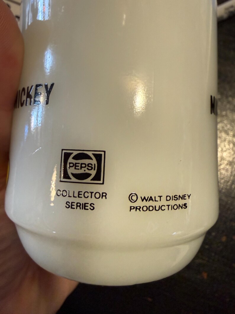 Pu&ograve; includere: Tazza in ceramica bianca della serie Collector Pepsi con il logo Walt Disney Productions. La tazza ha la scritta "Mickey" stampata sopra. Il logo Pepsi &egrave; in un quadrato nero.