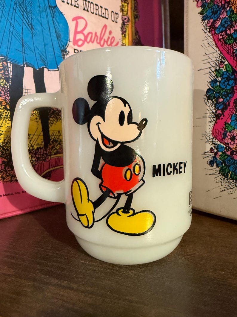 Pu&ograve; includere: Tazza in ceramica bianca con un'immagine colorata di Topolino. Topolino &egrave; raffigurato nel suo abito classico con pantaloncini rossi, scarpe gialle e guanti neri. La parola "MICKEY" &egrave; stampata in nero sulla tazza.