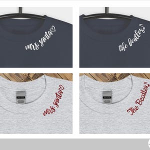 May include: Four t-shirts, two navy blue and two heather grey, with different text designs on the necklines. The designs are "mrs. santa" with a heart and "the beatles" with a musical note.