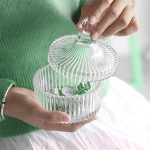 Puede incluir: Un tarro de vidrio transparente con un diseño acanalado y una tapa a juego. La tapa tiene forma de cúpula con un patrón decorativo.