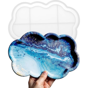 May include: A white silicone mold shaped like a cloud with six compartments. A finished resin tray in the shape of a cloud with a blue and white marbled design and gold glitter is shown next to the mold.