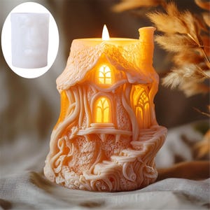 Puede incluir: Una vela detallada con forma de casita con chimenea, ventanas y una base con forma de árbol. La vela está hecha de cera beige claro y tiene un brillo cálido.