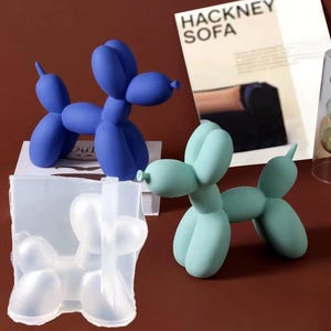 Può includere: Due sculture di cani a palloncino, una blu e una verde, con uno stampo in silicone trasparente di un cane a palloncino.