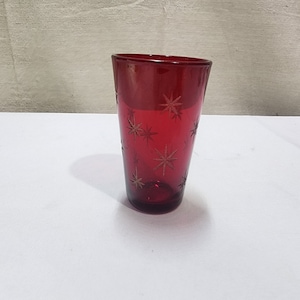 May include: A red glass drinking glass with a starburst pattern.