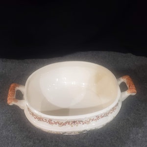 May include: White oval ceramic serving dish with brown floral pattern and two brown handles.