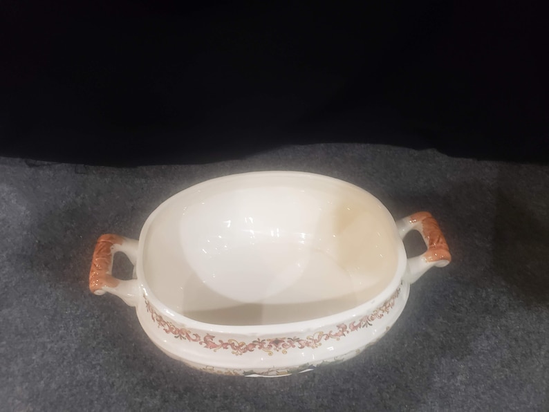 May include: White oval ceramic serving dish with brown floral pattern and two brown handles.