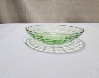May include: A green glass bowl with a textured, geometric pattern. The bowl is sitting on a white surface.