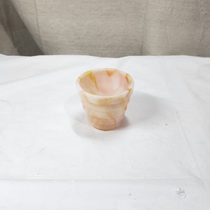 Op de afbeelding: Een kleine, decoratieve glazen beker met een gelaagd ontwerp. De beker heeft een mix van perzik-, witte en gele tinten. De buitenkant van de beker heeft een getextureerd, geribbeld uiterlijk en de binnenkant is glad.