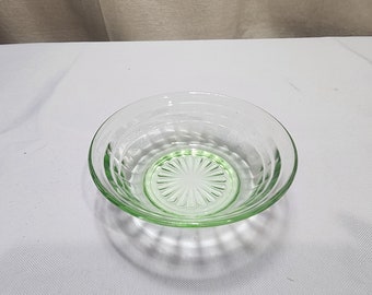 May include: A clear green glass bowl with a fluted design. The bowl has a scalloped edge and a circular pattern in the center.