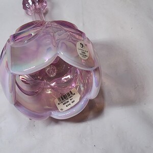May include: A pink iridescent glass flower with a stem. The flower is open and has a white interior. The flower has a sticker on the side that says "100 Years 1904".