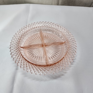 May include: A pink glass divided serving dish with a diamond pattern on the outer edge and a sunburst pattern on the inner sections.