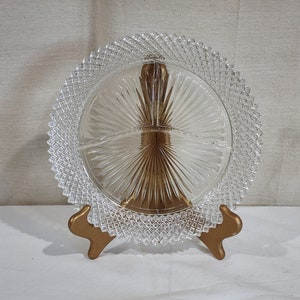 May include: A clear glass serving dish with a diamond-shaped pattern around the edge. The dish is divided into four sections and is on a gold-colored stand.
