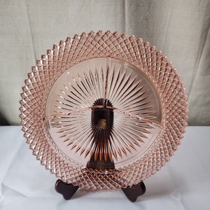 May include: A pink glass divided serving dish with a diamond pattern around the edge and a sunburst pattern in the center.