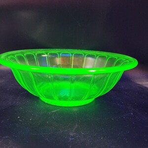 Può includere: Una ciotola di vetro verde con un design a scanalature. La ciotola è realizzata in vetro all'uranio, che brilla sotto una luce nera.