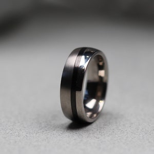 Anillo de bodas de titanio y fibra de carbono con diseño asimétrico. Ajuste cómodo. Grabado gratuito.