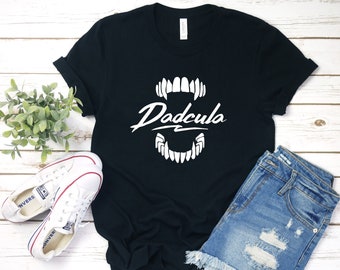 May include: Black t-shirt with a white graphic of a set of fangs and the text "Dadcula" in a stylized font.