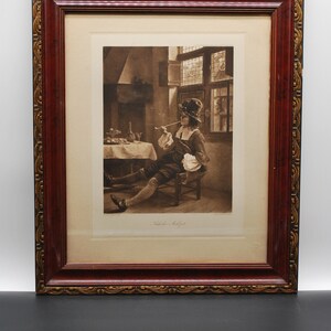 May include: A framed sepia-toned print of a man sitting in a chair, smoking a pipe, in a room with a fireplace and a window. The print is titled "Lede de Huijgen".