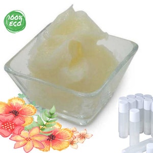 Peut inclure: Un bol en verre transparent rempli d'une substance crémeuse jaune clair. L'image montre également un ensemble de tubes de baume à lèvres transparents avec des bouchons blancs et un arrangement floral avec des fleurs rouges, oranges et jaunes. Un cercle vert avec le texte "100% ECO" est en haut à gauche.