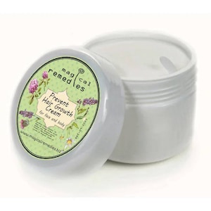 May include: A white jar of "Magical Remedies" Prevent Hair Growth Cream for face and body. The jar's lid is off, revealing the cream inside. The label features floral illustrations and the website address.