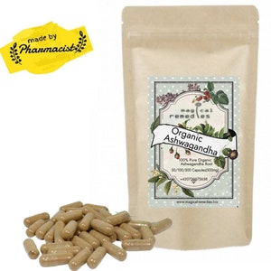 Könnte beinhalten: Eine Packung mit organischen Ashwagandha-Kapseln mit einem Etikett mit der Aufschrift "Organic Ashwagandha". Die Kapseln sind hellbraun und liegen neben der Packung. Die Packung ist hellbraun.