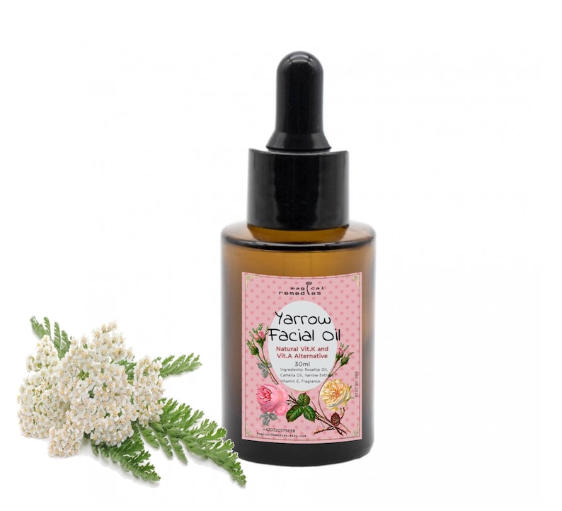 May include: A brown glass bottle of Yarrow Facial Oil with a black dropper, a pink label, and white text. The label includes floral illustrations. A sprig of white flowers and green leaves is to the left of the bottle.