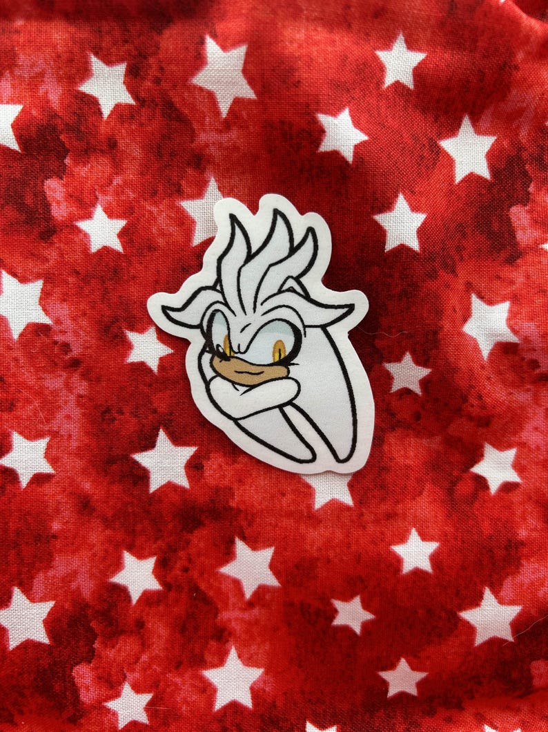 K&ouml;nnte beinhalten: Ein wei&szlig;er Aufkleber mit einer Cartoon-Zeichnung von Silver the Hedgehog aus der Sonic the Hedgehog-Videospielserie. Silver hat einen wei&szlig;en und grauen K&ouml;rper, gelbe Augen und einen wei&szlig;en und grauen, stacheligen Irokesenschnitt. Der Aufkleber befindet sich auf einem roten Hintergrund mit wei&szlig;en Sternen.