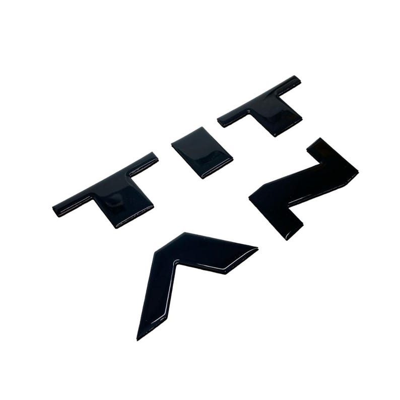 May include: Black plastic letters spelling out "TITAN" in uppercase. The letters are raised and have a glossy finish.