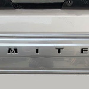 Könnte beinhalten: Nahaufnahme eines weißen LKW-Heckflügels mit silberner Verkleidung und dem Schriftzug "LIMITED" in schwarzen Buchstaben.
