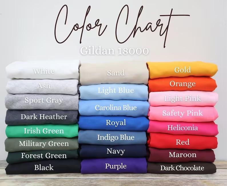 May include: Color chart of Gildan 18000 apparel in various colors. The chart displays folded sweatshirts in shades of white, gray, blue, green, and more. Text labels identify each color, including "White," "Black," and "Red."