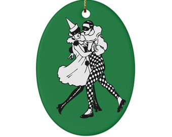 May include: A green oval ceramic ornament with a black and white illustration of a couple in masquerade costumes dancing.