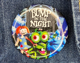 May include: A blue and white button with a picture of characters from the show "Bump in the Night". The button has the show's title in white letters on a black background.
