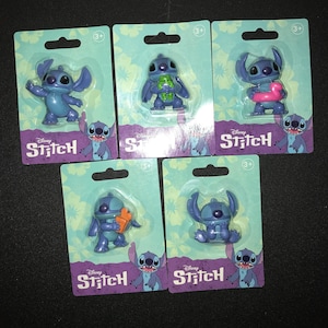 May include: Five blue Stitch figurines in their original packaging. Each figure is a different pose, some holding accessories. The packaging is light blue with a floral pattern and the Disney Stitch logo.