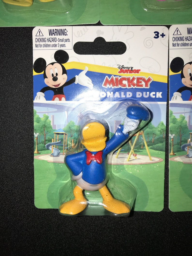 Peut inclure: Une figurine en plastique de Donald Duck de Mickey Mouse Clubhouse de Disney Junior. Donald Duck porte sa chemise de marin bleue signature avec un n&oelig;ud papillon rouge et un pantalon jaune. La figurine est emball&eacute;e dans une bo&icirc;te &agrave; bulles en plastique avec un fond vert et blanc. L'emballage comprend un avertissement de risque d'&eacute;touffement et une recommandation d'&acirc;ge de 3 ans et plus.