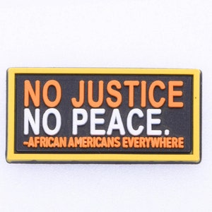 May include: A black and yellow rectangular patch with the text "NO JUSTICE NO PEACE." in orange and white letters. The text "AFRICAN AMERICANS EVERYWHERE" is printed in smaller white letters below the main text.