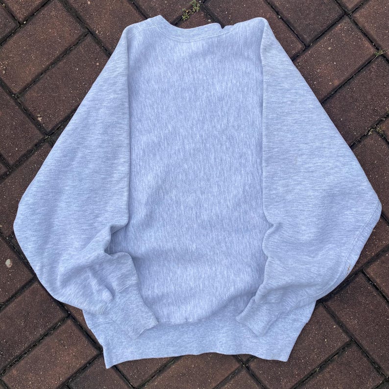 May include: A light gray sweatshirt with long sleeves and a crew neck.