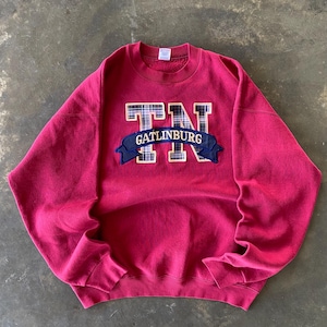 Può includere: Una felpa di colore rosso cremisi con una grande toppa ricamata che presenta le lettere "TN" in un motivo a quadri e il testo "Gatlinburg" in uno stendardo blu navy.