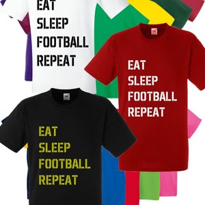 May include: A selection of t-shirts in various colours featuring the text "Eat Sleep Football Repeat" in white or yellow lettering.