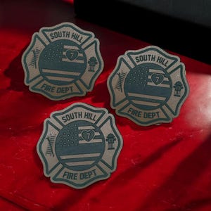 May include: Three brown leather patches with a green fire department emblem. Each patch features a stylized American flag with a heart containing the number 7. The text "SOUTH HILL FIRE DEPT" is printed on each patch.